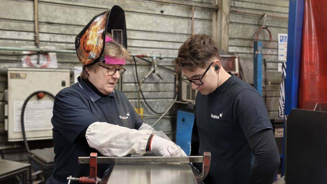 une soudeuse avec son masque de soudure et son apprenti