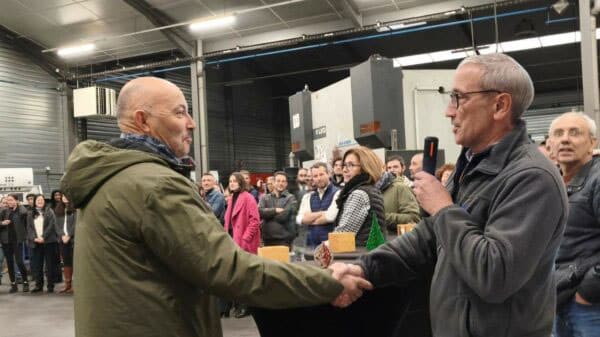 le président Jean-Pierre Gomez sert la main de Patrice devant une équipe d'environ 70 collaborateurs
