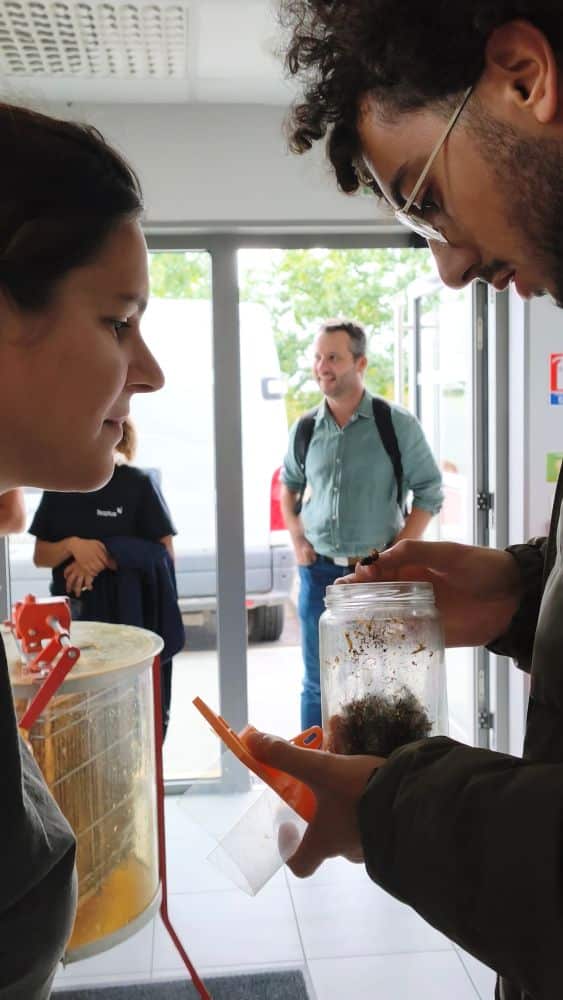 une homme et une femme souriant regardent un piège contenant des frelons asiatiques ; en arrière plan, 2 autres salariés teoplus